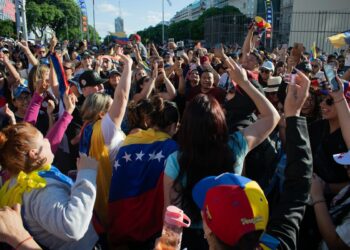 Vibrant crowd of Venezuelans celebrating with flags and cheers in an urban street setting.