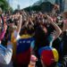 Vibrant crowd of Venezuelans celebrating with flags and cheers in an urban street setting.