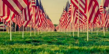 us a flags on green grass field during daytime