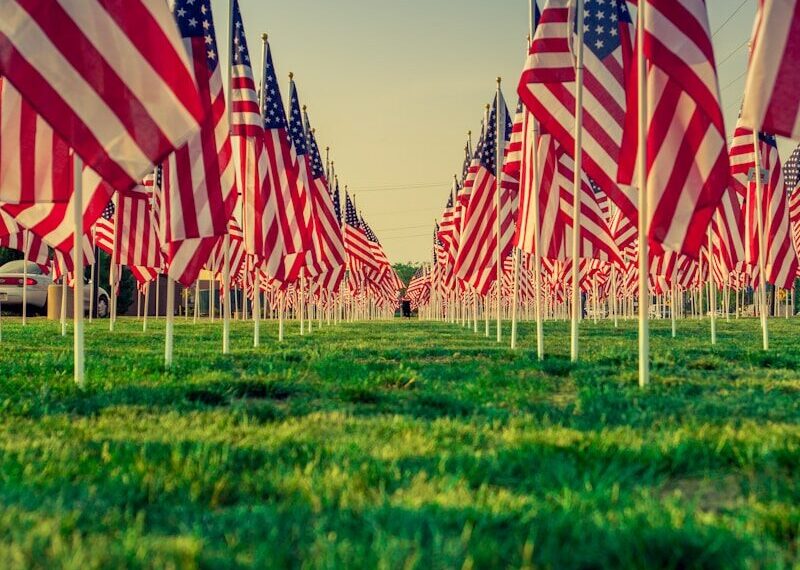 us a flags on green grass field during daytime