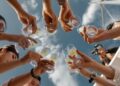 people holding clear glass bottles during daytime