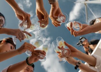 people holding clear glass bottles during daytime